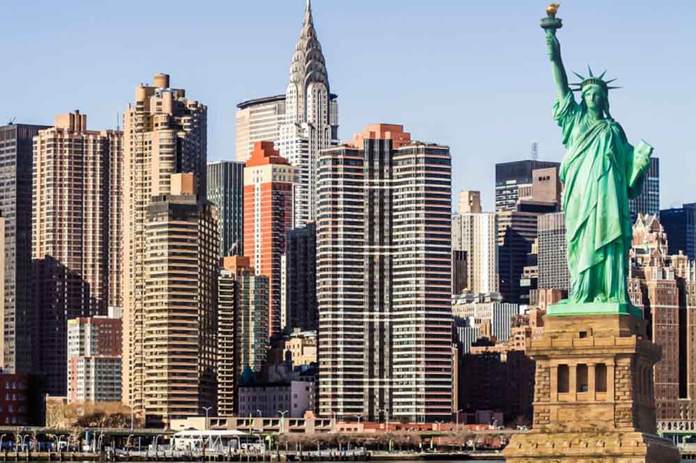 The Statue of Liberty stands tall in the foreground, with New York City's skyscrapers, including the Chrysler Building, dominating the skyline behind her.
